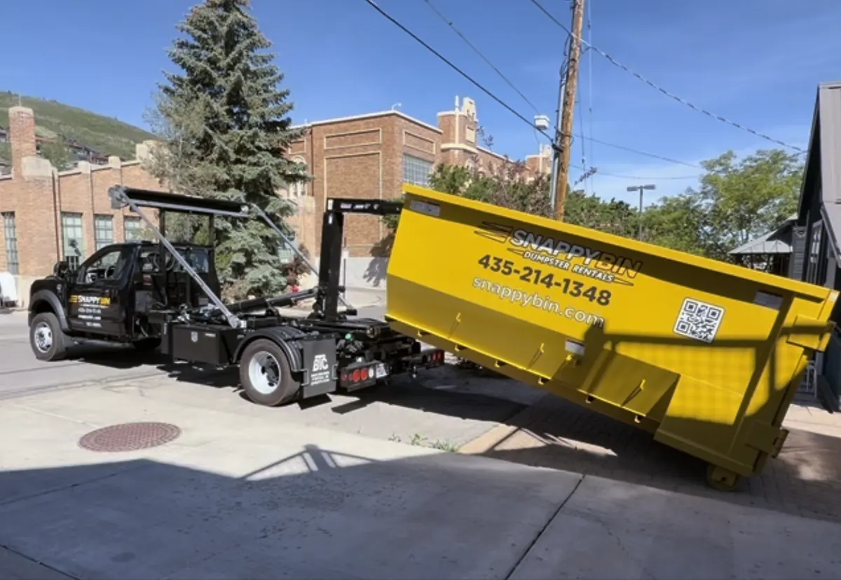Snappy Bin truck lowering a yellow dumpster during delivery